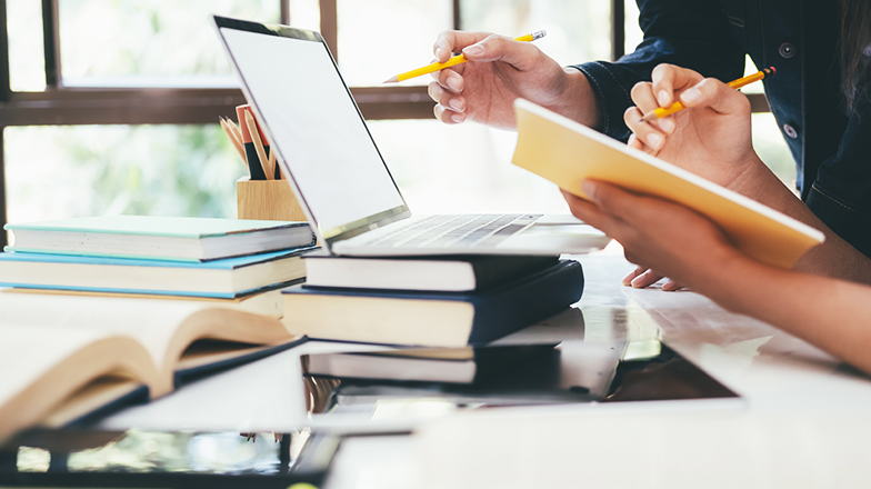 책들이 널려 있고, 노트북을 보며 필기를 하고 있는 모습